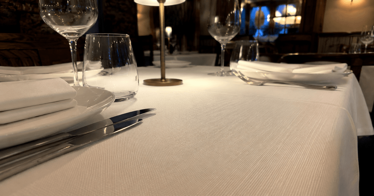 Tavolo di ristorante apparecchiato con tovaglia candida e ben stirata in tessuto contract resistente ai lavaggi