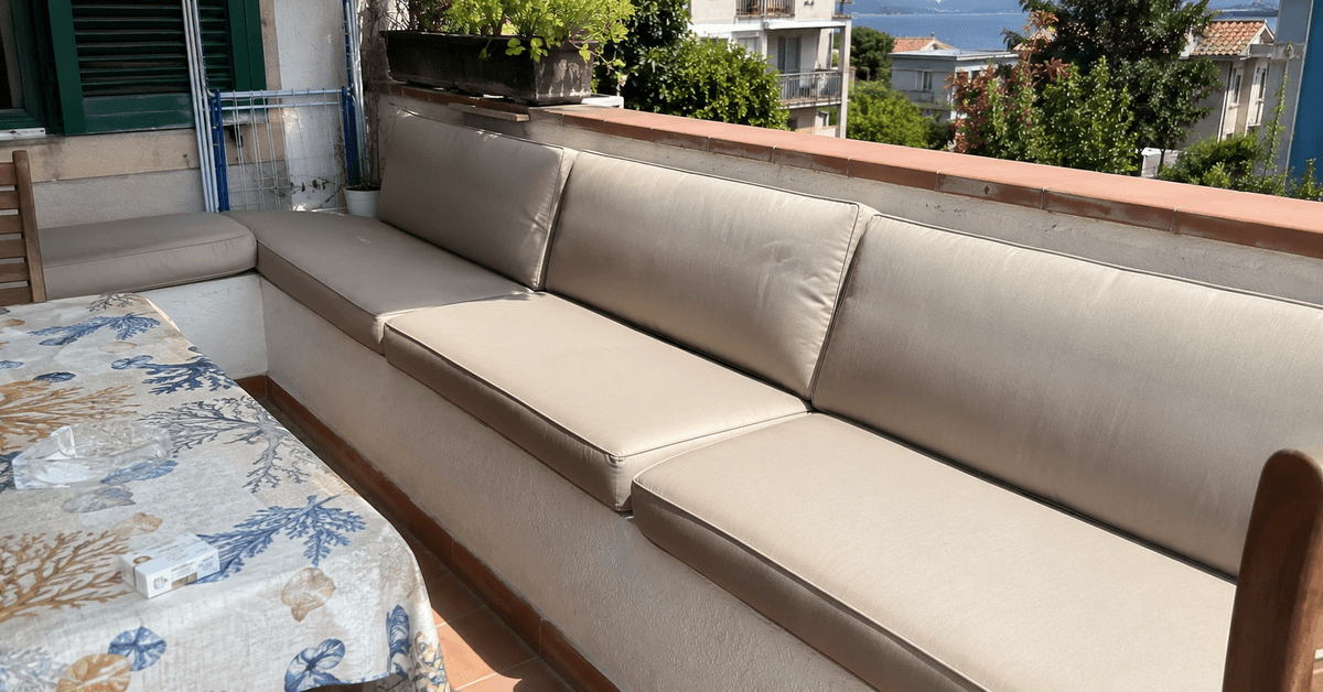 Panca da esterno con cuscini su misura color sabbia su una terrazza luminosa
