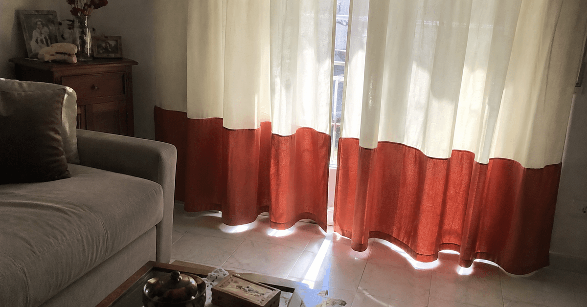 Tenda bicolore con parte alta avorio e banda terracotta in basso in un soggiorno luminoso