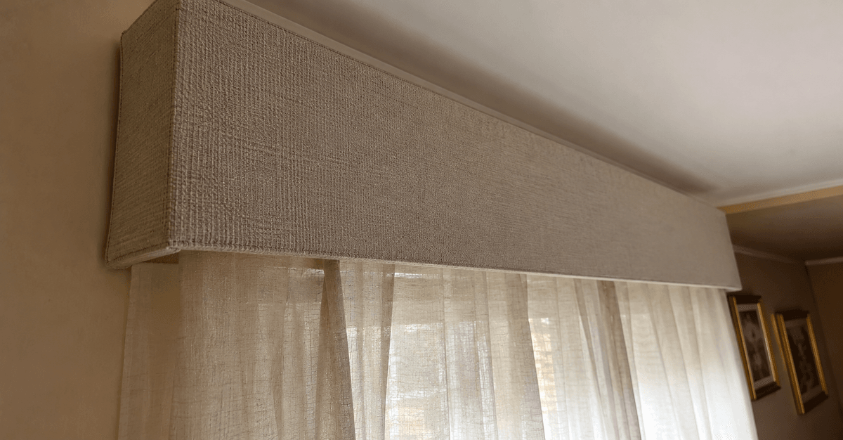 Finestra ampia con una mantovana moderna e sobria in tinta neutra calda sopra tende in lino, ambiente luminoso e contemporaneo