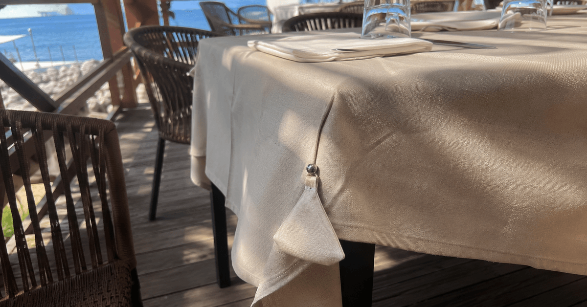 Tavolo apparecchiato di un dehor estivo con tovaglia ben tesa fissata da fermatovaglia a clip