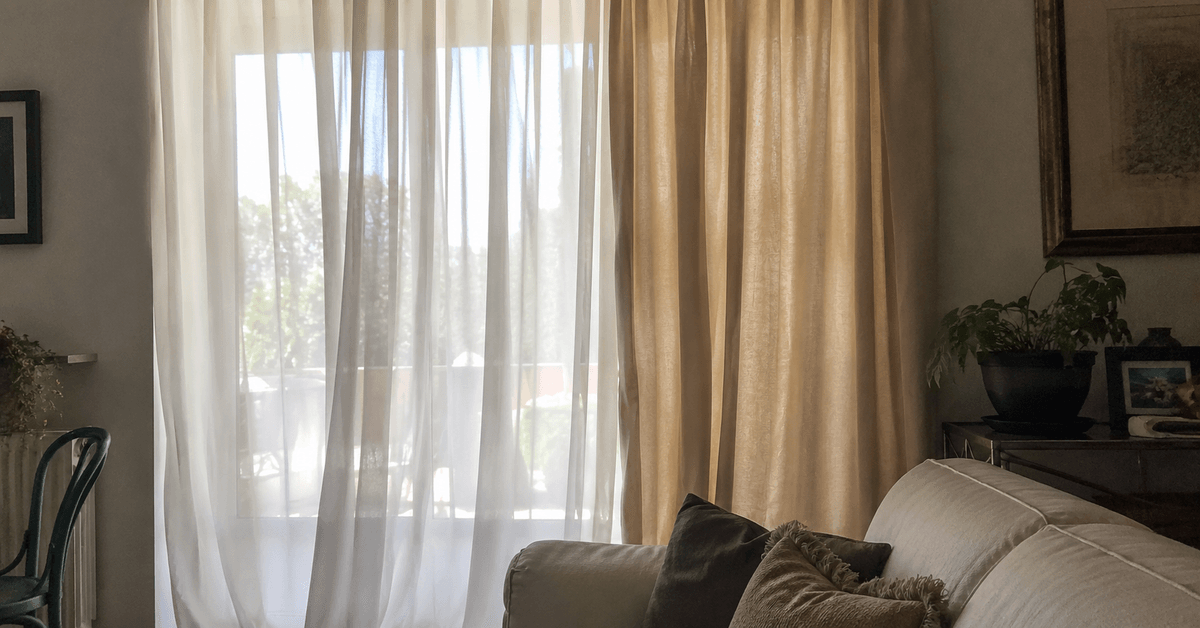 Finestra di soggiorno con tende a doppio strato, voile chiaro davanti e tenda in lino più pesante dietro