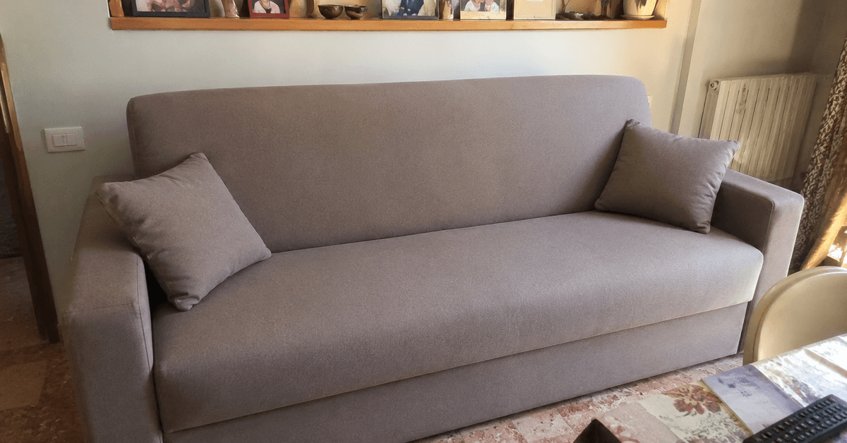 Divano letto rifoderato con tessuto nuovo resistente in un ambiente domestico, aspetto rimesso a nuovo con luce naturale calda