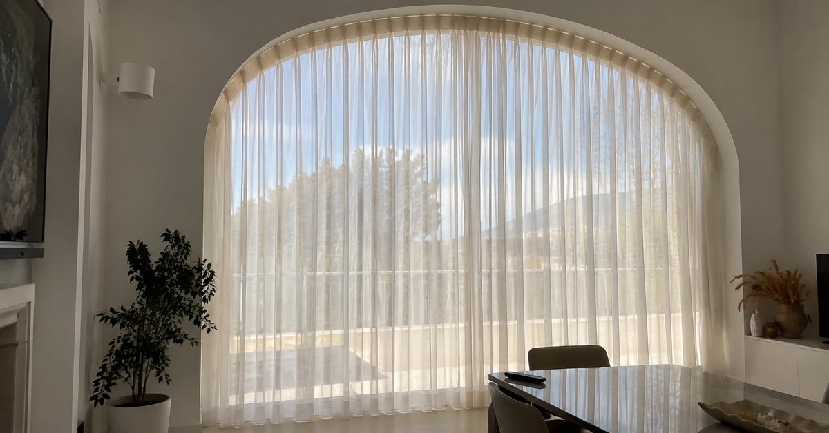 Finestra ad arco a tutta altezza vestita con tende su misura che ne rispettano la curva