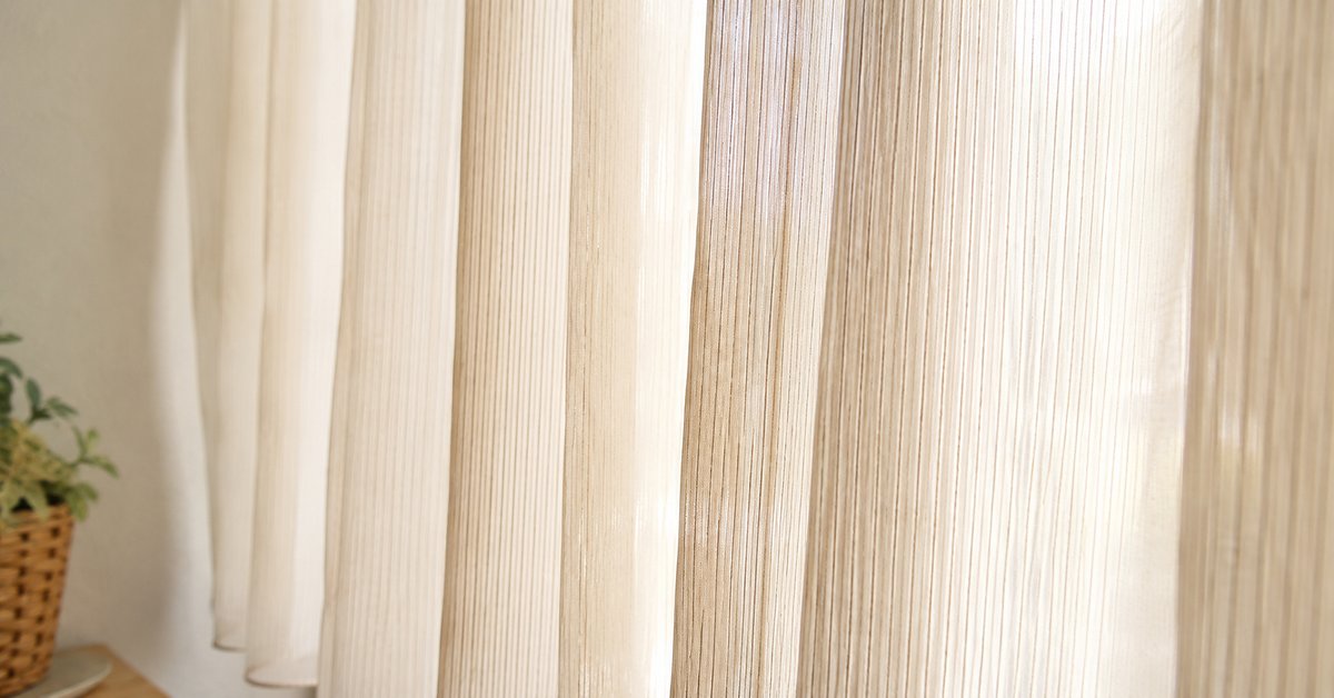 Tende a righe verticali sottili tono su tono davanti a una finestra alta e luminosa