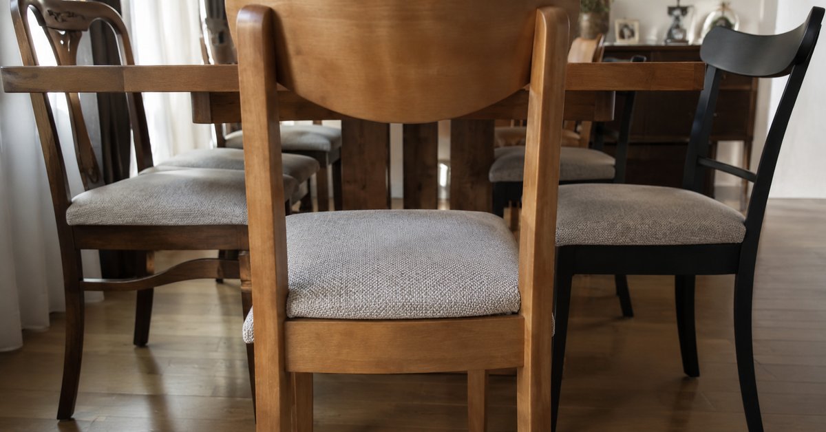 Sala da pranzo con sedie di forme e legni diversi ma sedute rivestite con lo stesso tessuto coordinato
