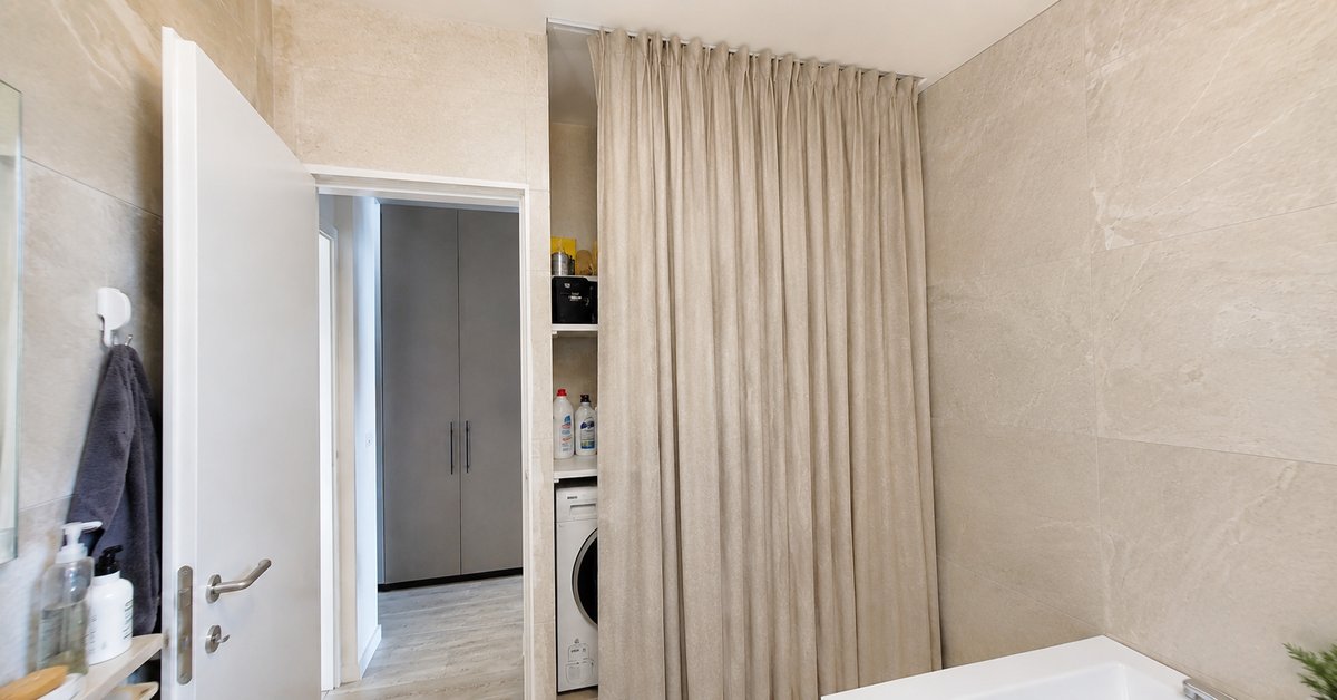 Tenda su misura a tutta altezza su binario a soffitto che nasconde la lavatrice in un angolo bagno, tessuto abbinato alle piastrelle
