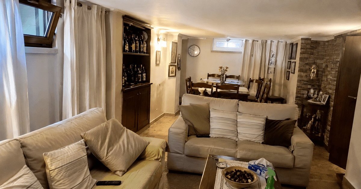 Tavernetta seminterrata arredata con tende leggere e cuscini sfoderabili in tessuti antimuffa, ambiente asciutto e accogliente
