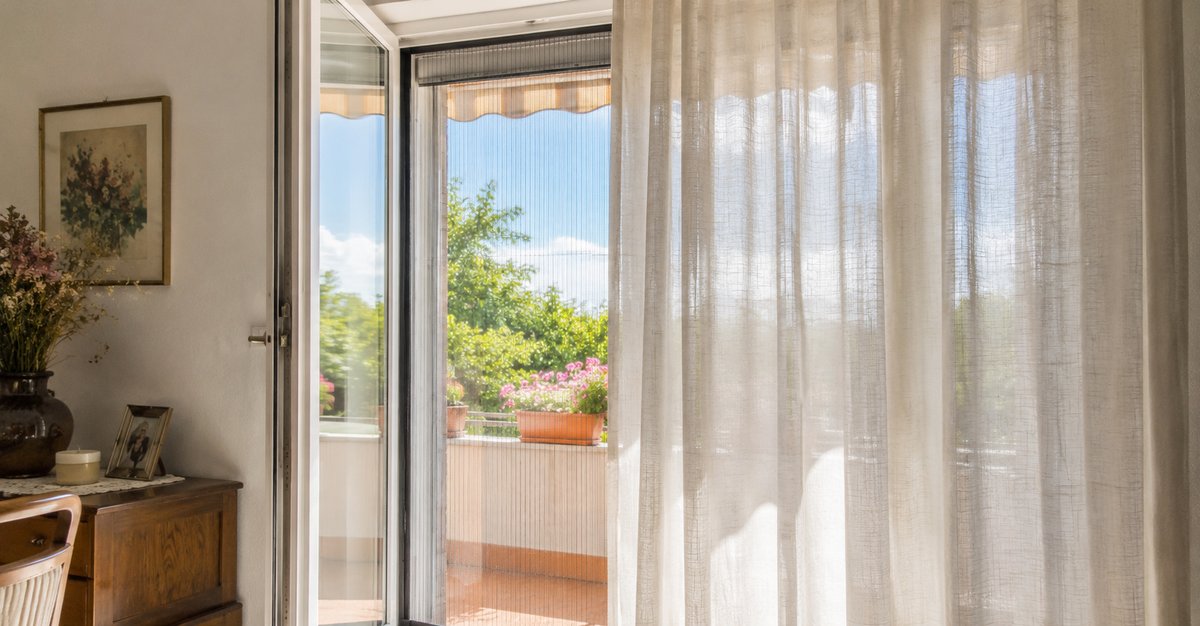 Tenda montata davanti a una zanzariera a rullo sulla stessa finestra senza impigliarsi