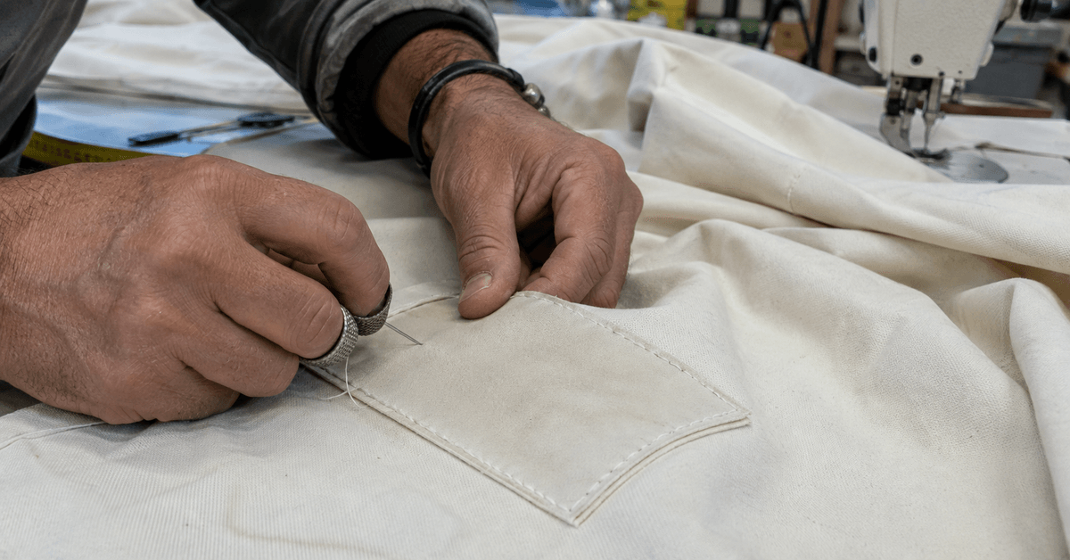 Mani in laboratorio che cuciono una toppa su un telo di tendalino nautico in tela acrilica