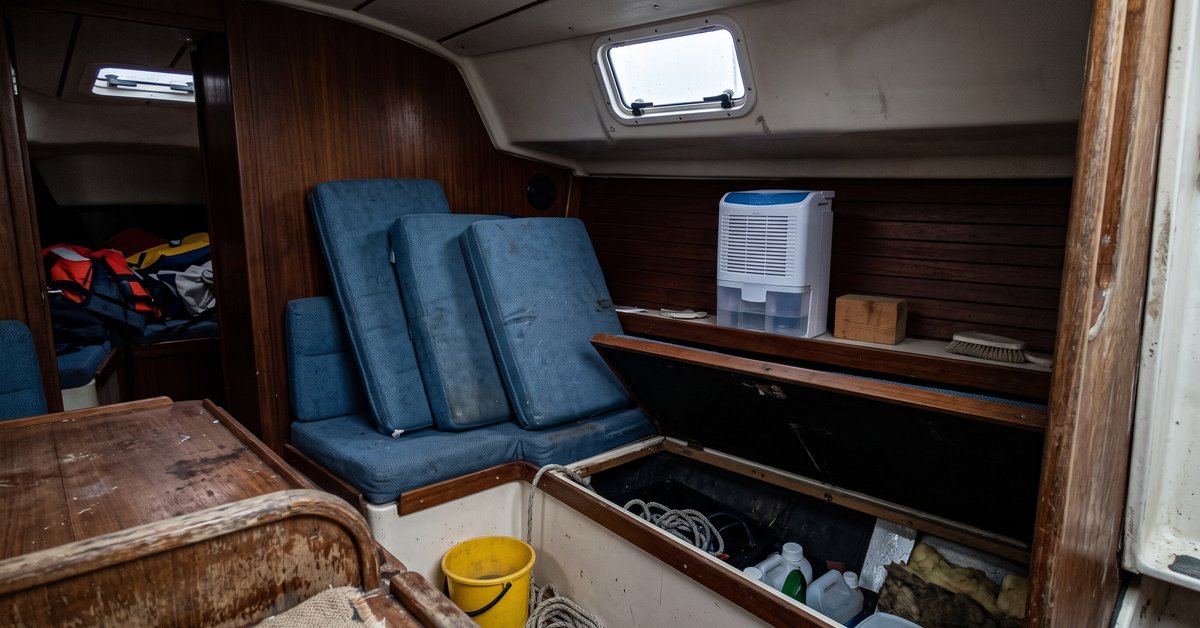 Dinette di una barca in rimessaggio invernale con i cuscini sollevati per arieggiare e un deumidificatore a sali su un ripiano