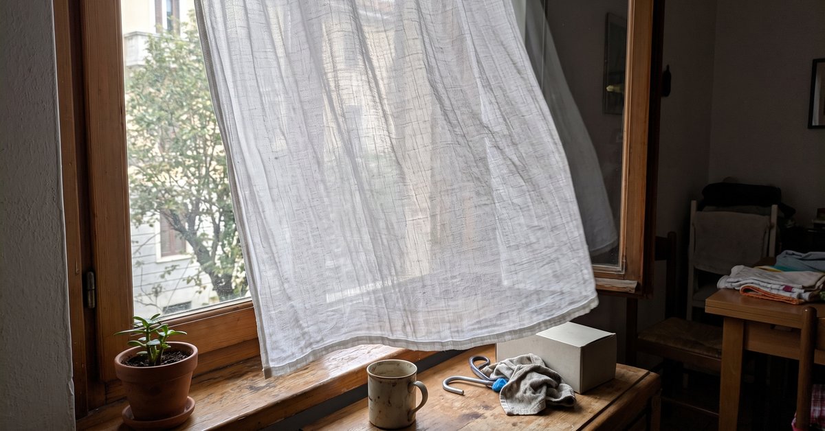 Tenda in garza di cotone bianca e leggera in controluce davanti a una finestra di casa