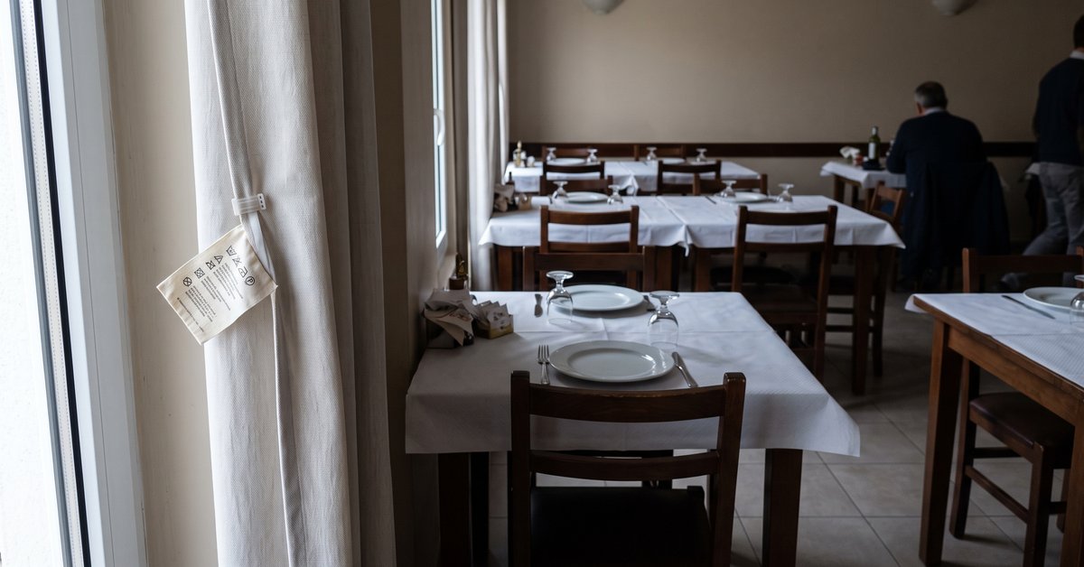 Tenda in tessuto ignifugo chiaro accanto alla finestra di un ristorante con il cartellino di certificazione del tessuto in primo piano